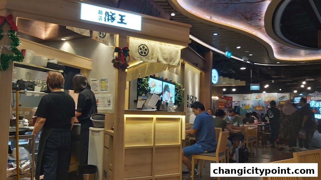 A Japanese restaurant counter with staff preparing food and customers dining.