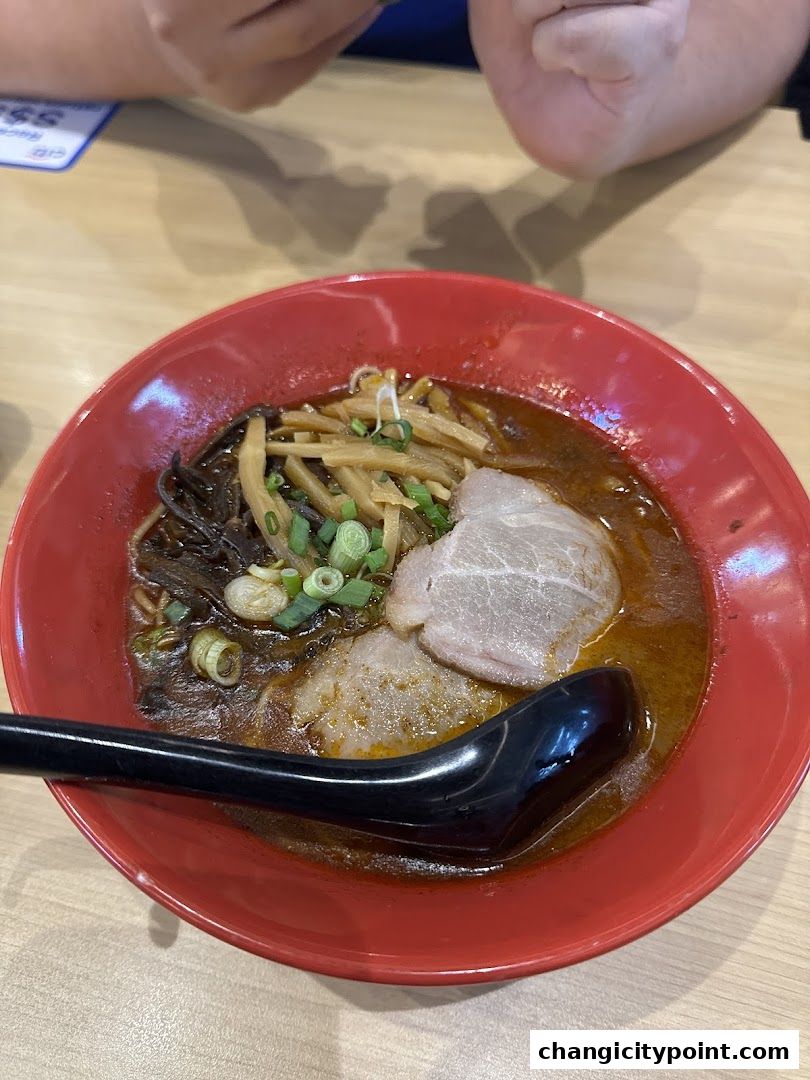 A steaming bowl of ramen with pork, bamboo shoots, and green onions.