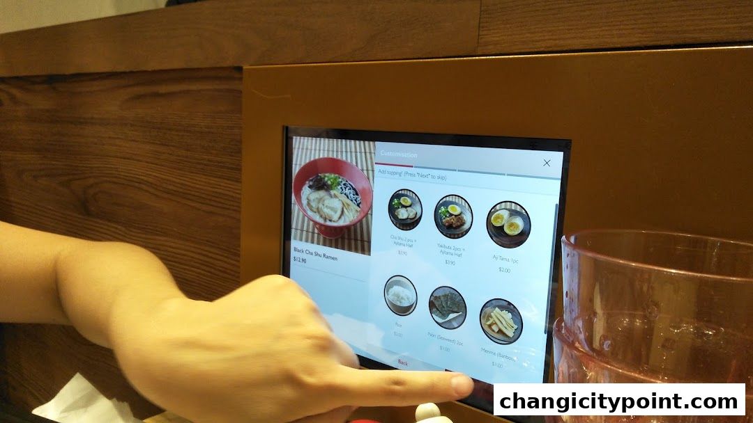 A hand interacts with a digital menu displaying ramen customization options.