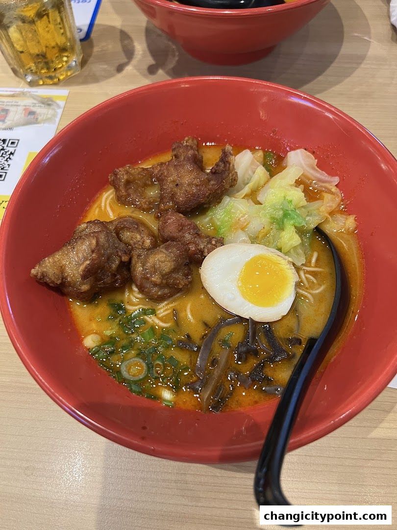A delicious bowl of ramen with fried chicken, egg, and vegetables.