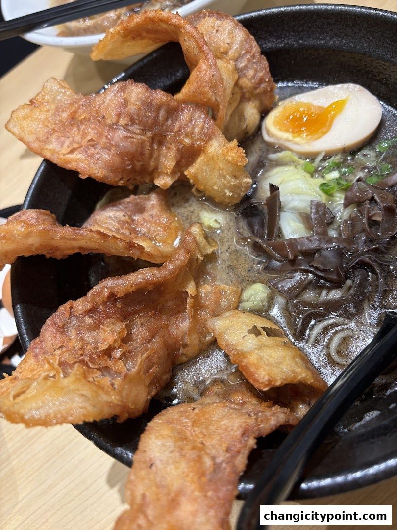 A close-up of a delicious ramen bowl with crispy toppings and a soft-boiled egg.