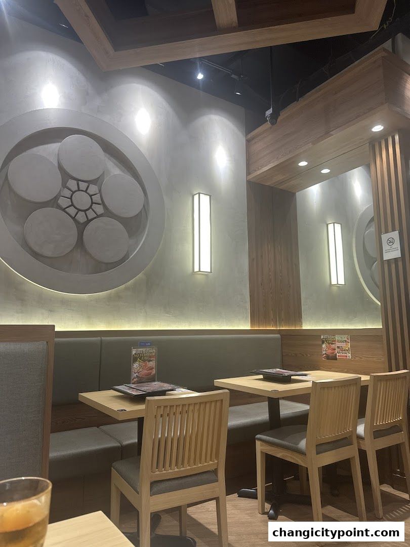 Interior of a restaurant with wooden chairs and tables, and decorative wall art.