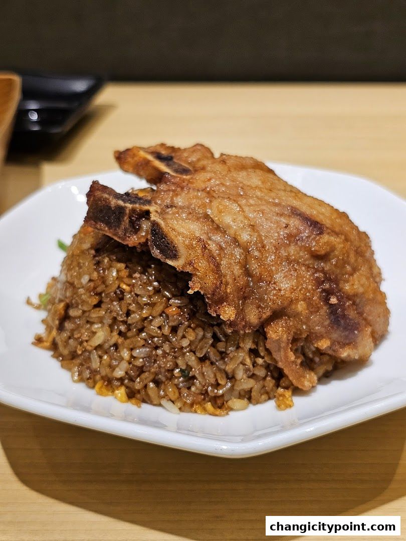 A plate of fried rice topped with a crispy fried pork chop.