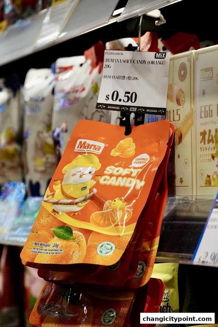 A close-up of orange-flavored soft candy packets displayed on a shelf in a store.