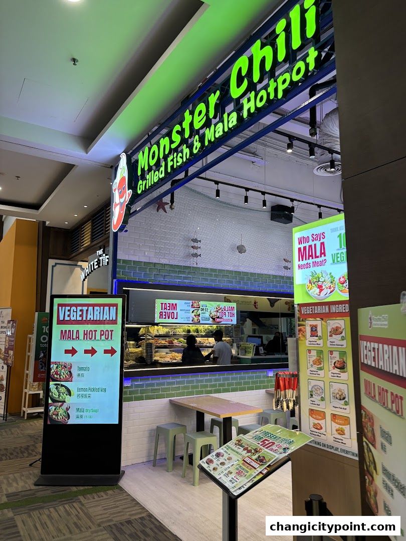 The exterior of Monster Chili Grilled Fish and Mala Hotpot, featuring a vibrant sign and digital menu displays.