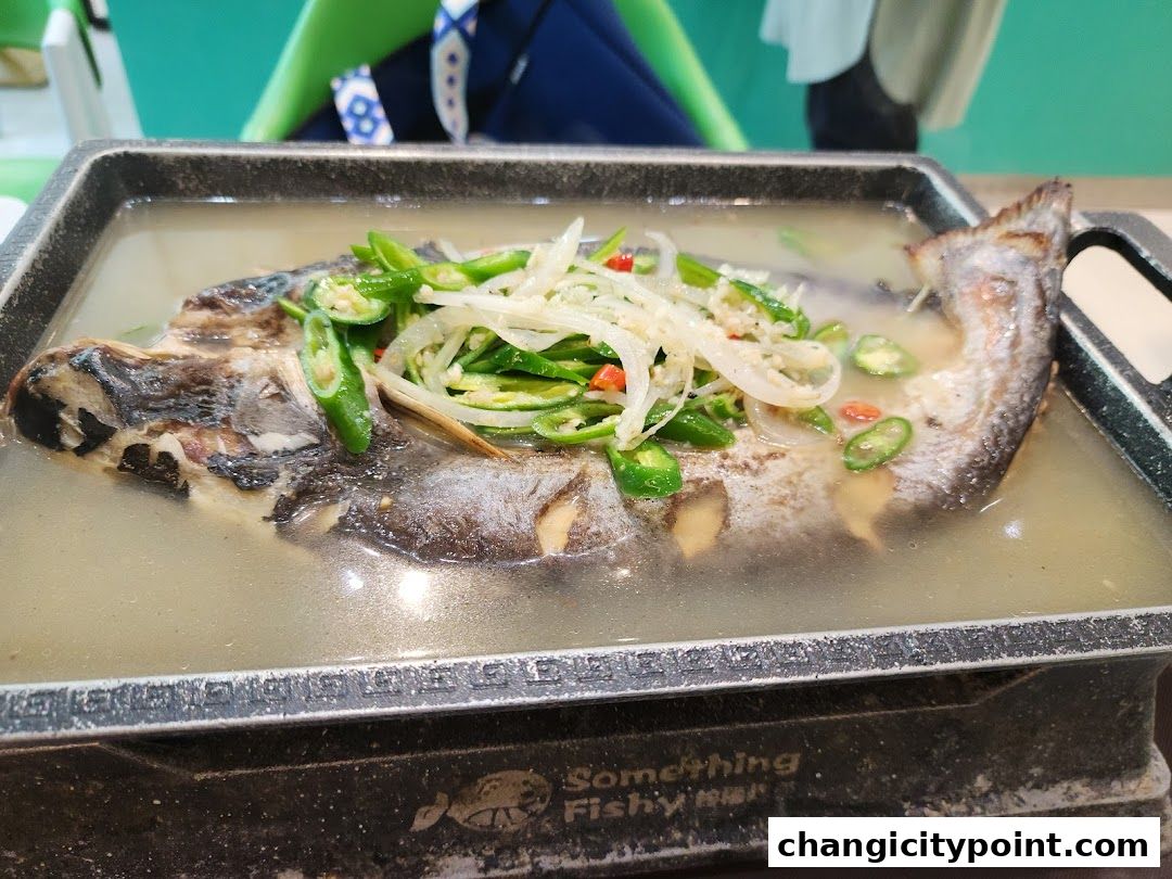 A whole grilled fish with chili and onions in a hot pot.