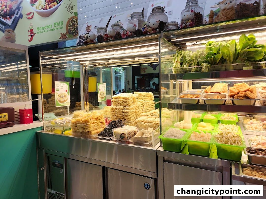 A display of fresh ingredients for hotpot and grilled fish, including vegetables, noodles, and tofu.