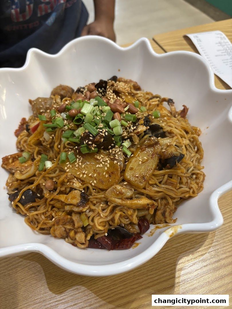 A close-up of a large bowl of spicy noodles with various toppings and garnishes.