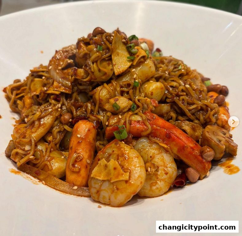 A close-up shot of a spicy noodle dish with shrimp, sausages, and peanuts.