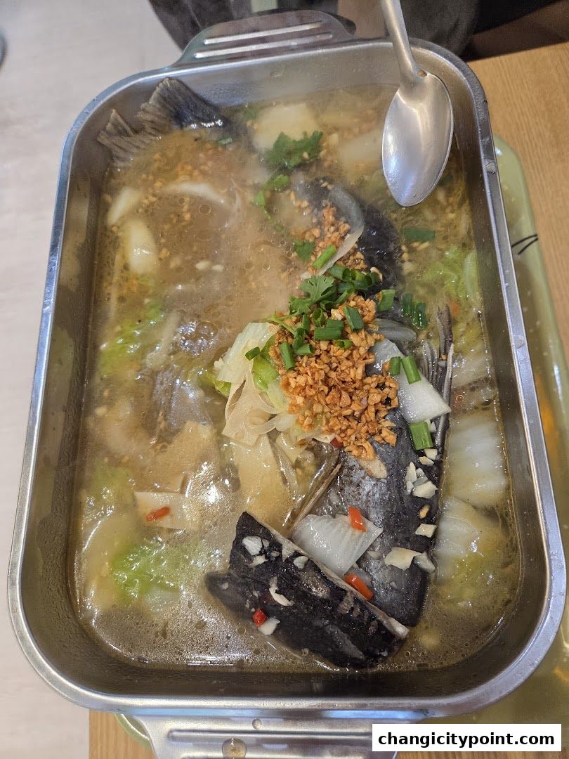 A steaming hot pot of grilled fish with vegetables and spices.