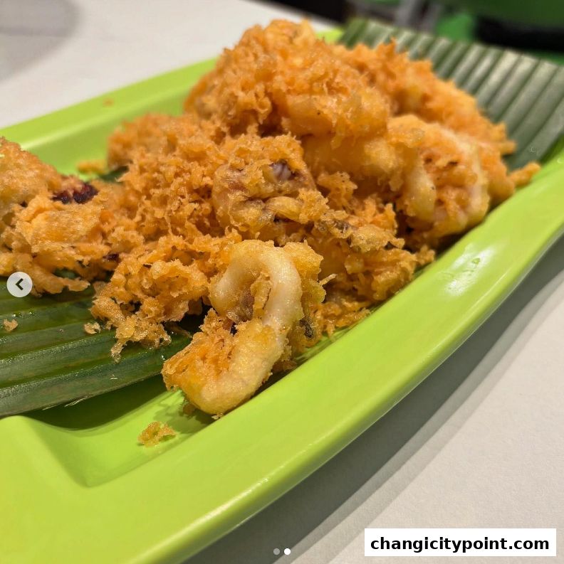 Crispy fried calamari served on a banana leaf on a bright green plate.