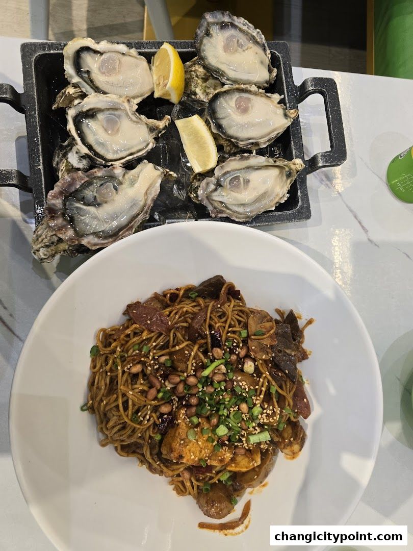 A platter of fresh oysters and a bowl of spicy noodles with peanuts and scallions.
