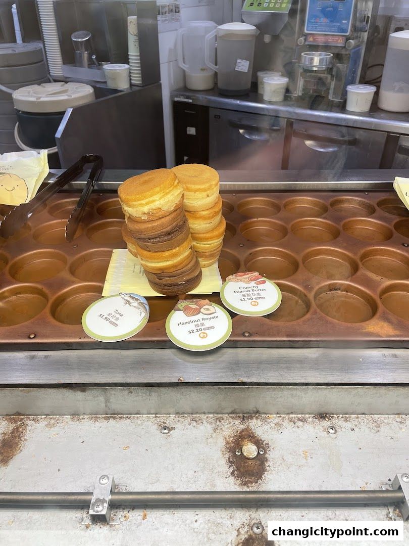 Stacks of freshly made round pastries with various flavor labels displayed.