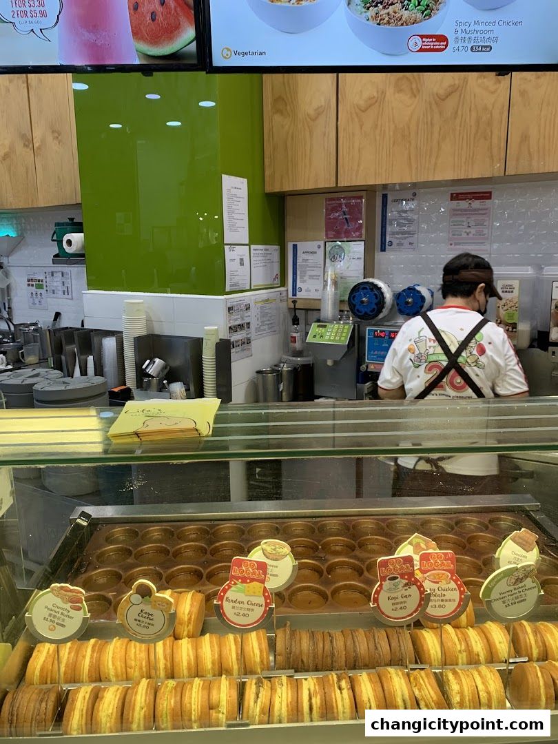 A display of freshly made sweet pastries and a food counter with staff.