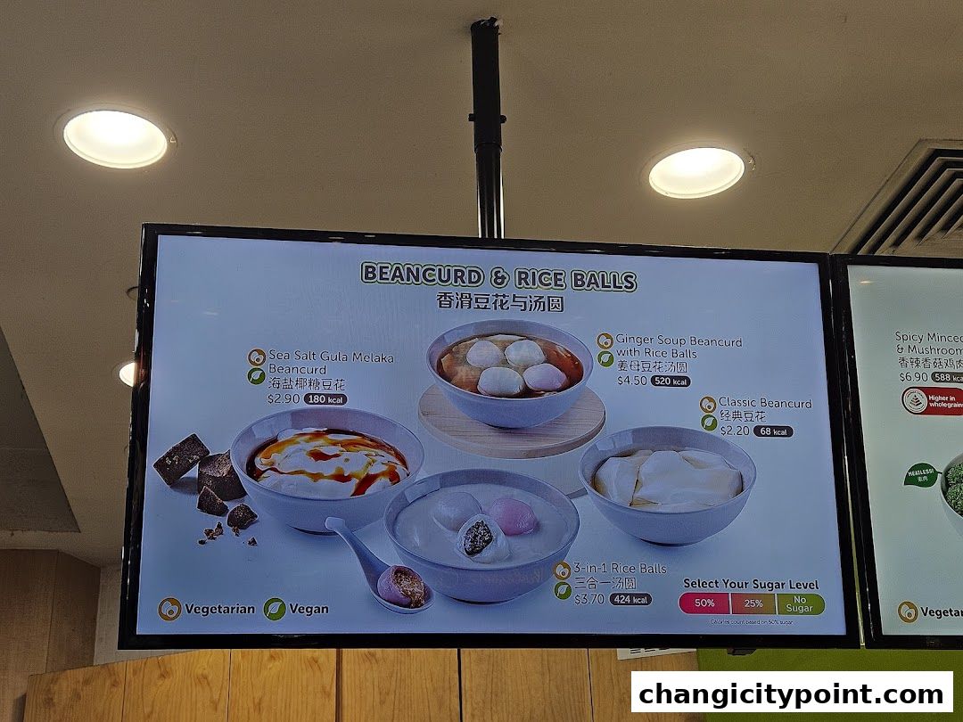 A digital menu board displaying beancurd and rice ball dishes with prices and calorie information.