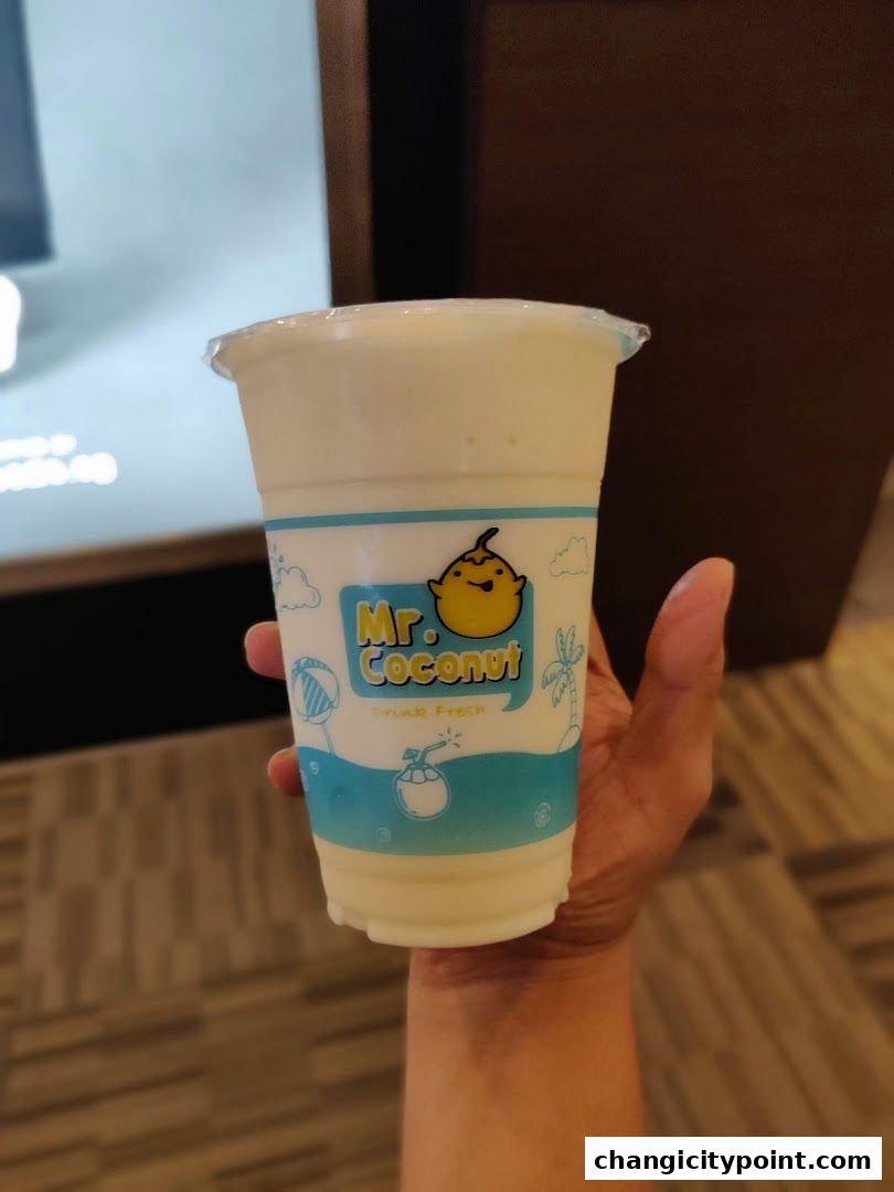 A hand holds a Mr. Coconut drink with the shop's logo visible.