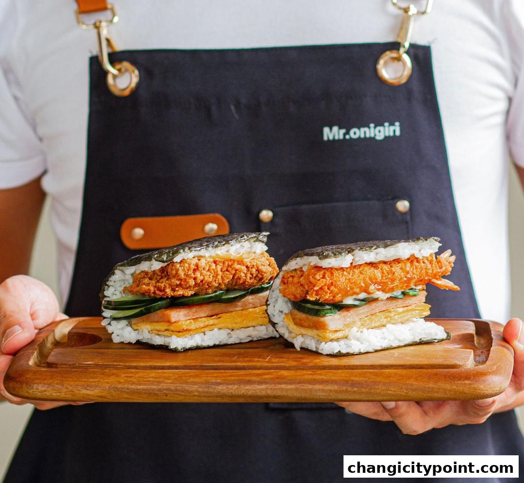 Two delicious onigiri sandwiches with fried chicken and shrimp on a wooden tray.