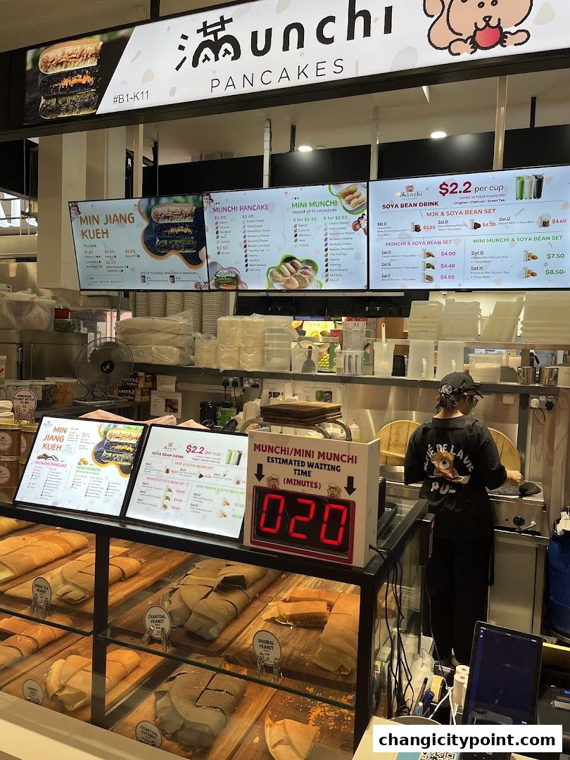 A display of pancakes and menu boards at Munchi Pancakes, with a waiting time indicator.