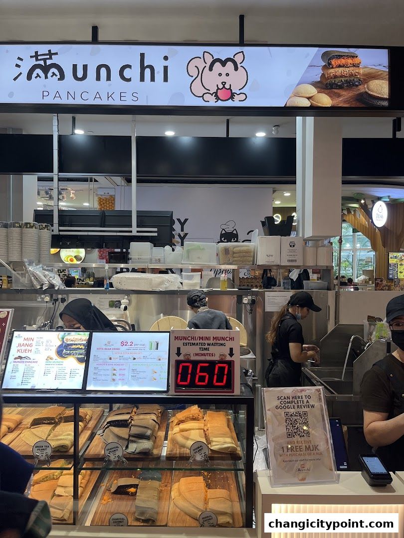 A shop front display of Munchi Pancakes with various pancake options and a waiting time indicator.