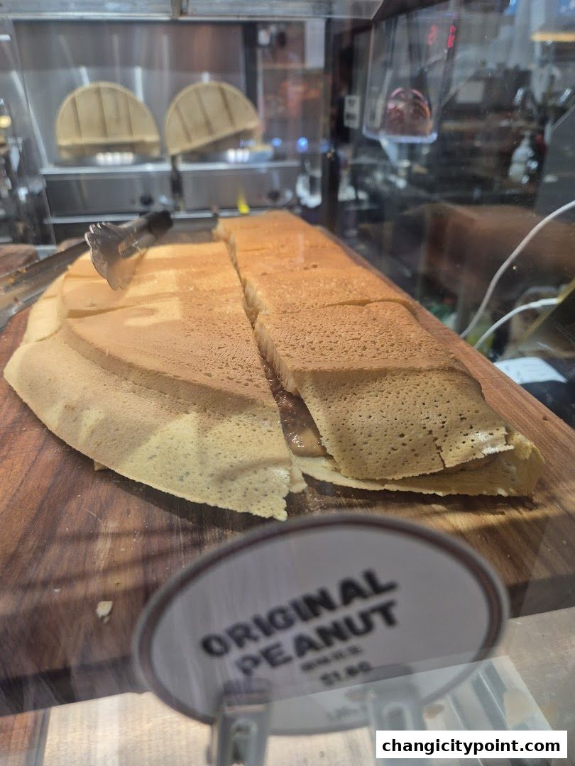 A close-up of a freshly made pancake filled with peanut butter, sliced and ready to serve.