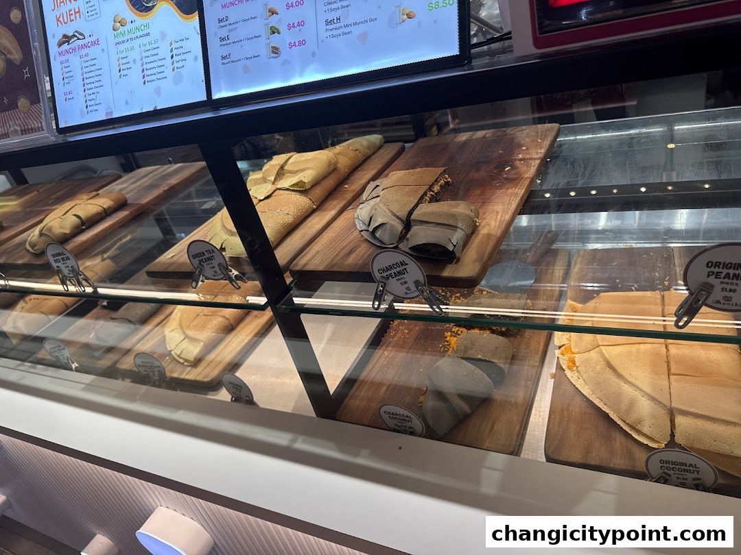 A display case filled with various types of pancakes and a digital menu board above.