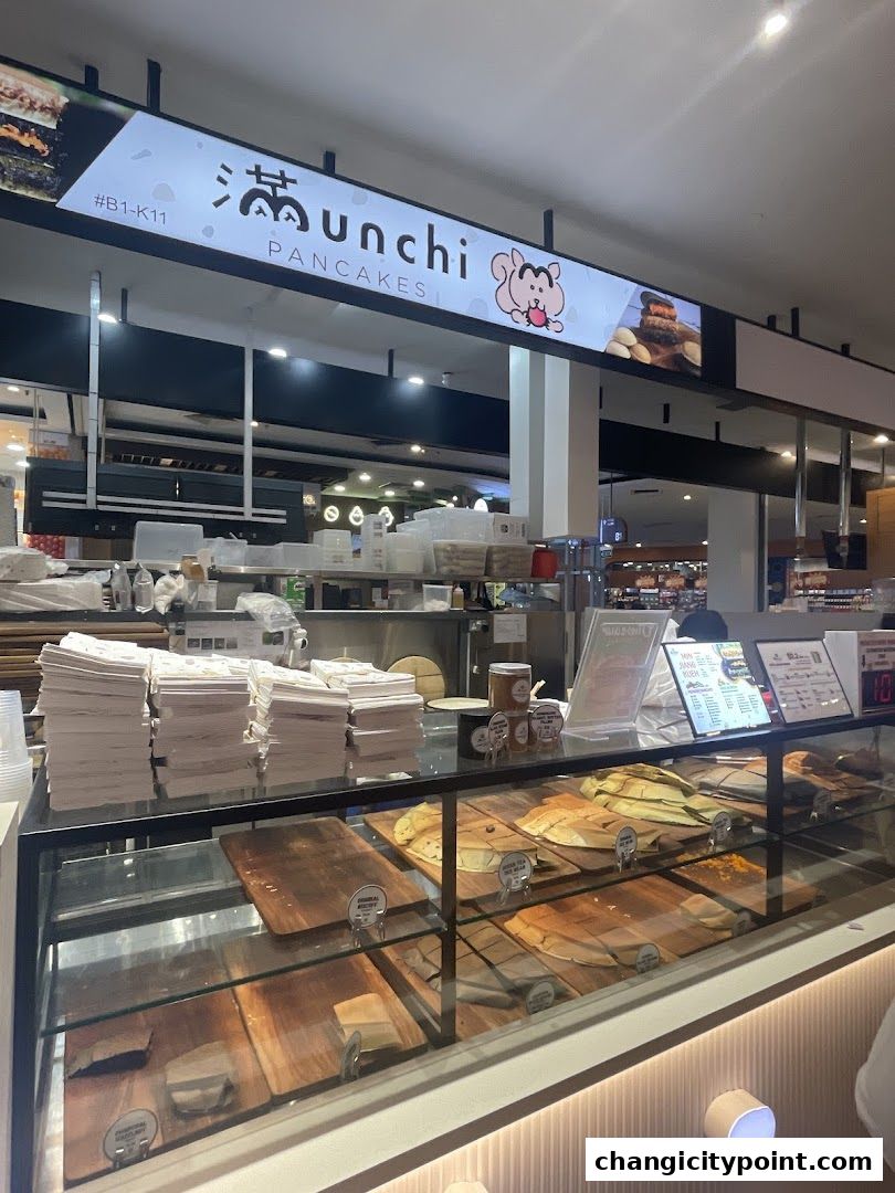 The exterior of Munchi Pancakes shop with a display of pancakes and menu boards.