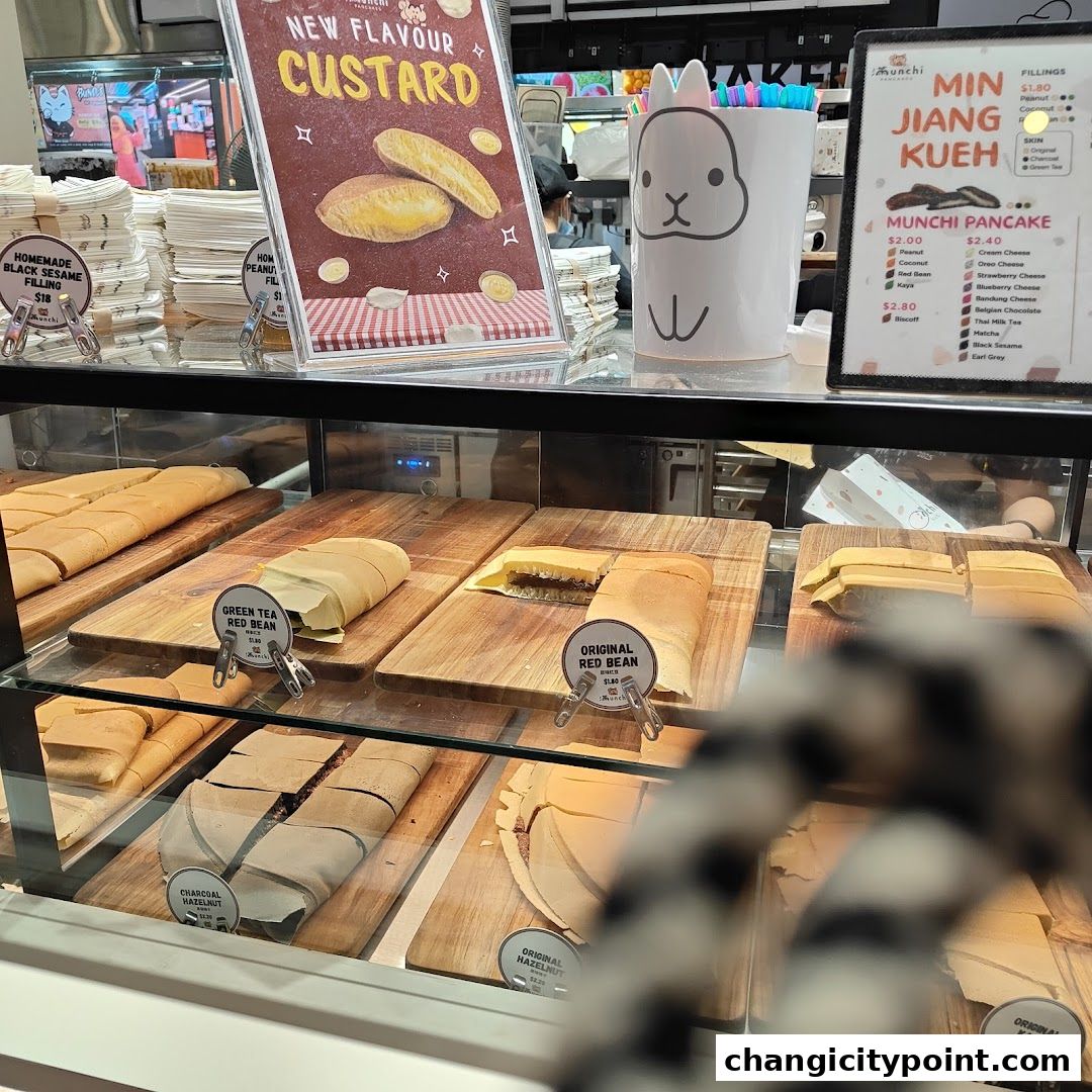A display case filled with various flavors of pancakes and a sign advertising a new custard flavor.