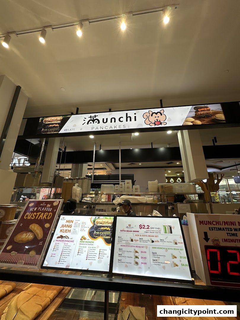 A shop front display for Munchi Pancakes, showcasing menus and pancake offerings.