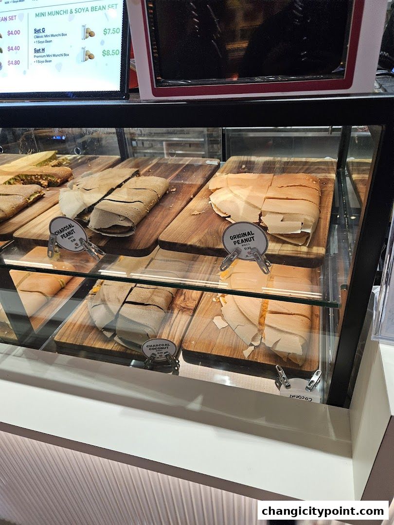 A display case filled with various types of pancakes and a digital menu board above.