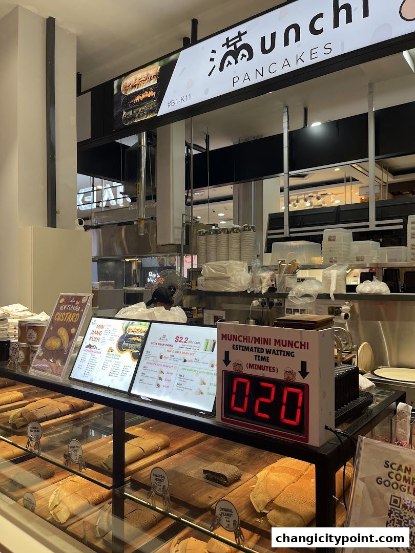 A display counter at Munchi Pancakes showcasing various pancake flavors and a digital waiting time indicator.