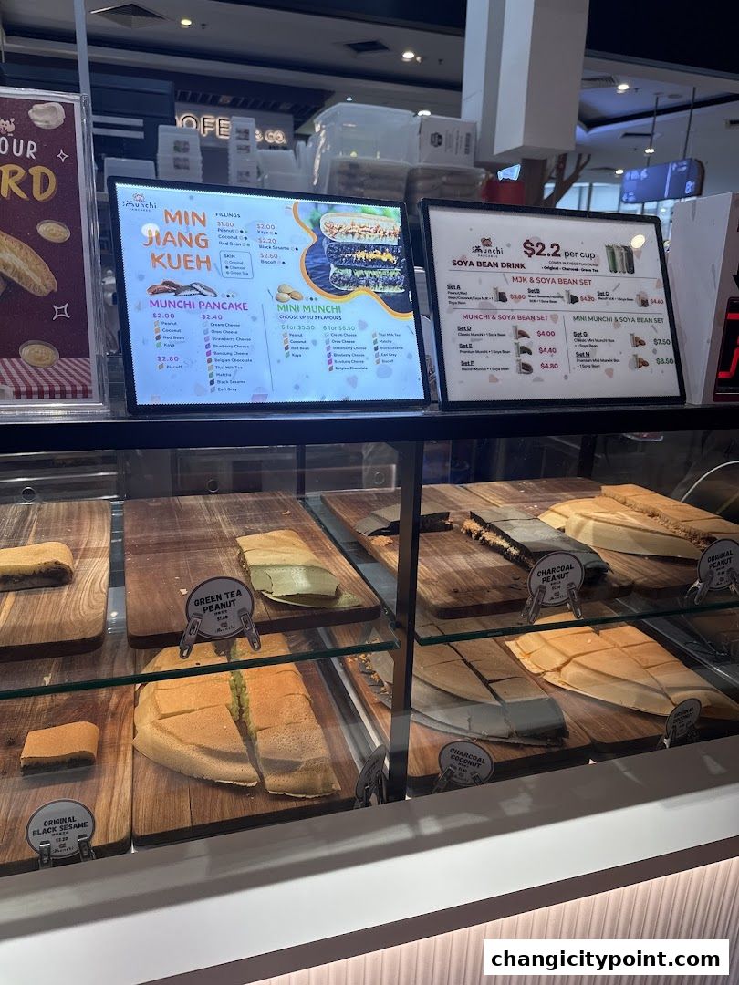 A display case filled with various pancakes and a menu board showing prices and options.