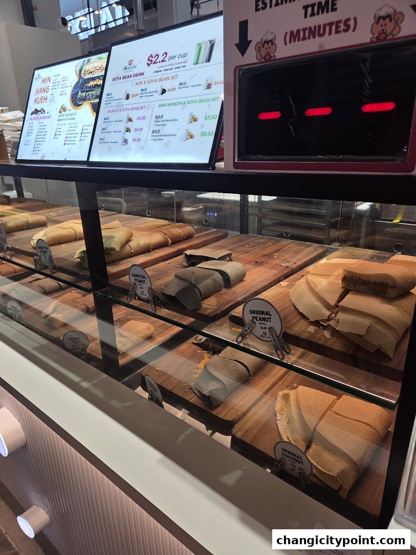 A display case filled with various types of pancakes and a menu board showing prices.