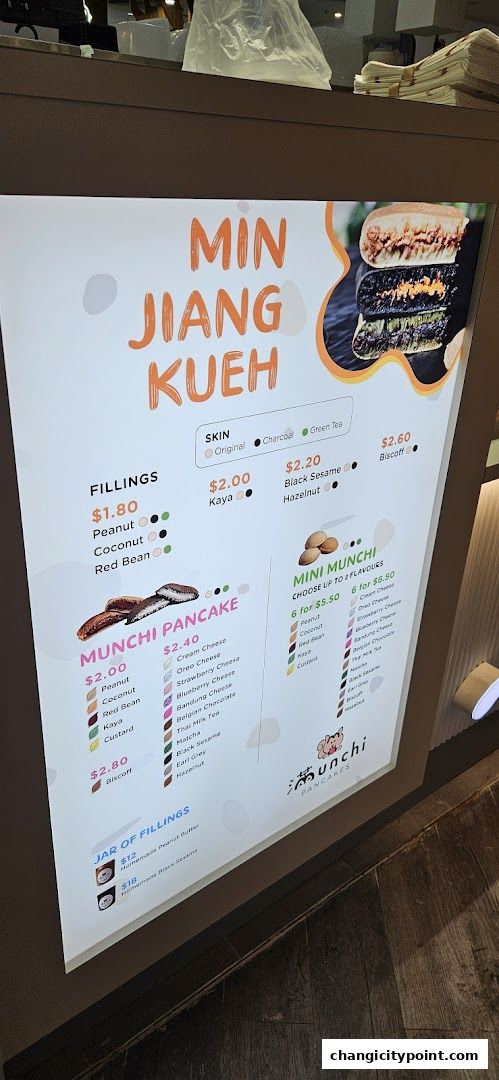 A brightly lit menu board displaying various pancake flavors and fillings from Munchi Pancakes.