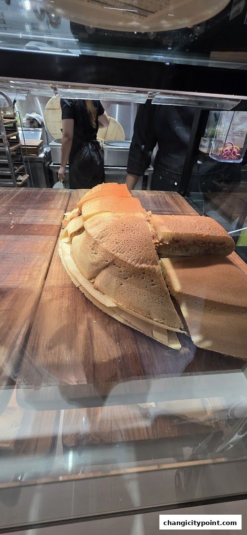 A close-up of freshly made pancakes, sliced and displayed on a wooden surface.