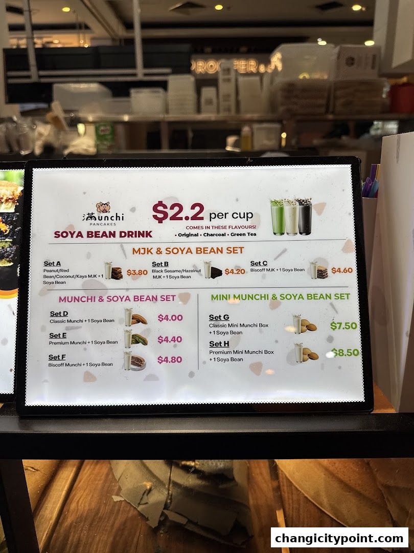 A menu board for Munchi Pancakes featuring soya bean drinks and various set meals.
