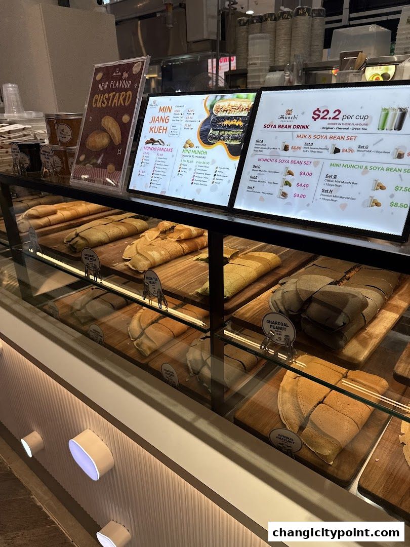 A display case filled with various pancakes and a digital menu board showcasing prices and options.