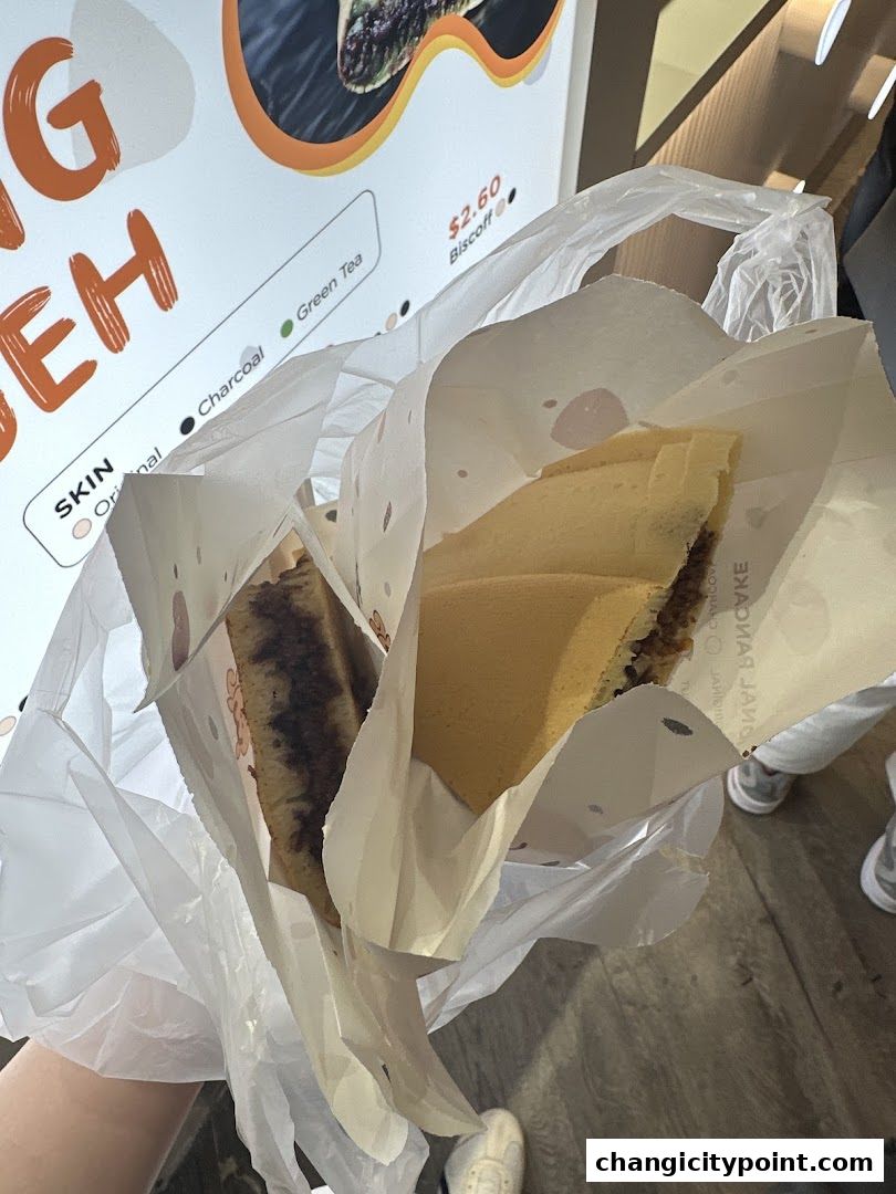 Two freshly made pancakes in paper packaging, held in a plastic bag.