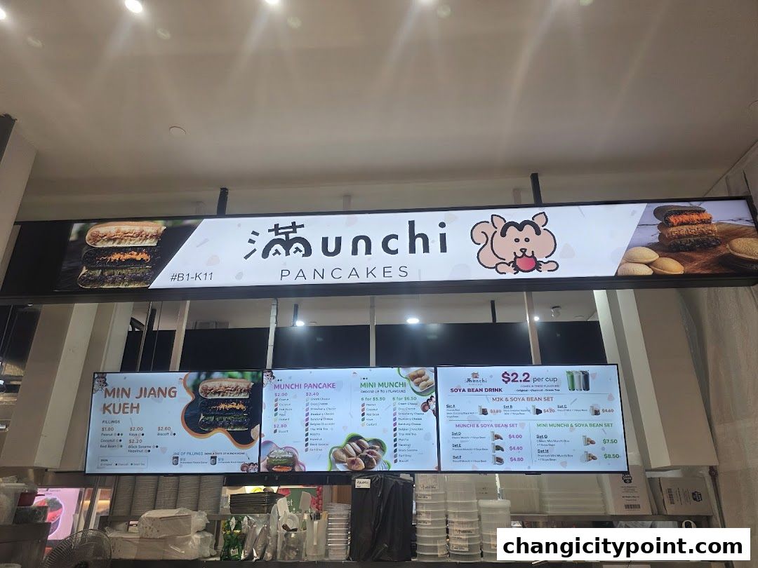 A digital menu board for Munchi Pancakes, showcasing various pancake and kueh options.