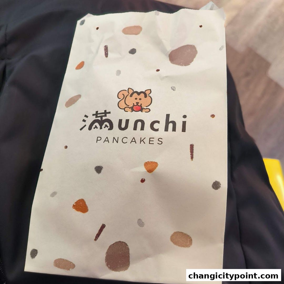 A paper bag with the Munchi Pancakes logo and a cute squirrel illustration.