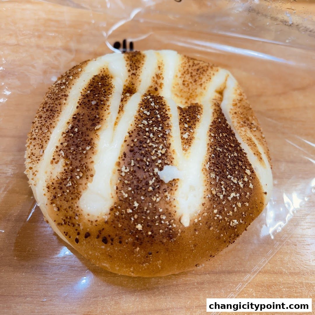 A close-up of a freshly baked bun with white icing and sprinkled toppings.