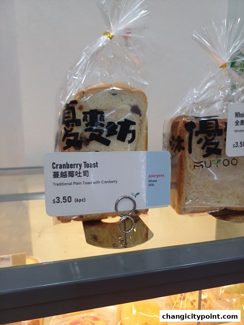 Packaged cranberry toast and whole wheat bread displayed in a bakery case.