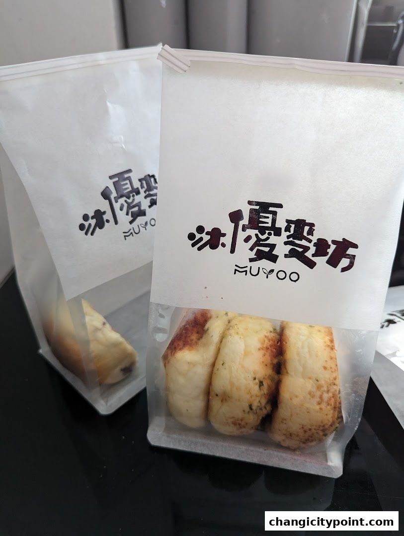 Two paper bags from Muyoo Bakery, one showing baked goods inside.