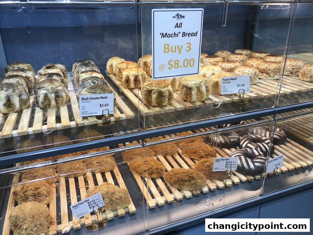 A display of various baked goods, including mochi bread and pork floss buns.