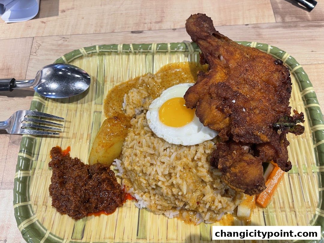 A delicious plate of Nasi Lemak with fried chicken, egg, and sambal.