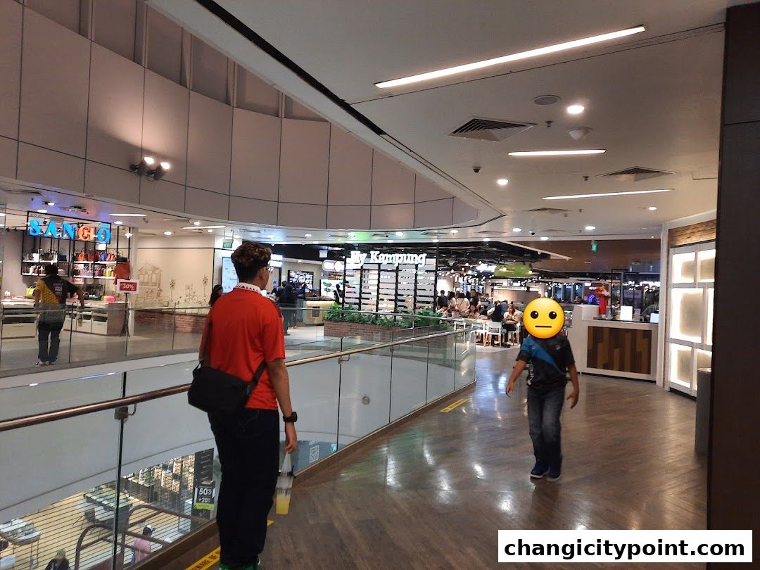 A view of a shopping mall interior with people walking and shops visible.