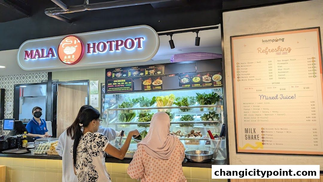 Customers ordering at a Mala Hotpot stall with a refreshing fruit juice menu.