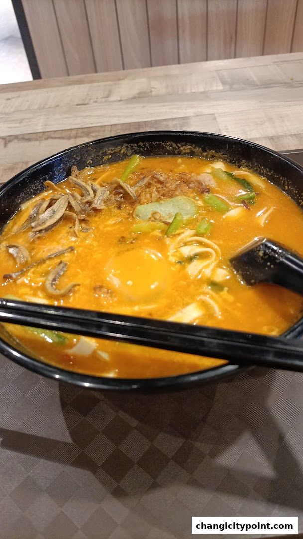 A close-up shot of a delicious bowl of noodles with a runny egg and anchovies.