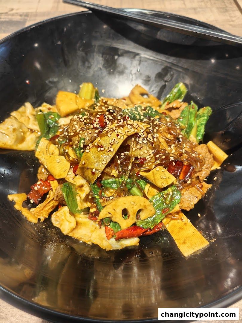 A close-up of a flavorful stir-fry dish with noodles, vegetables, and meat in a black bowl.