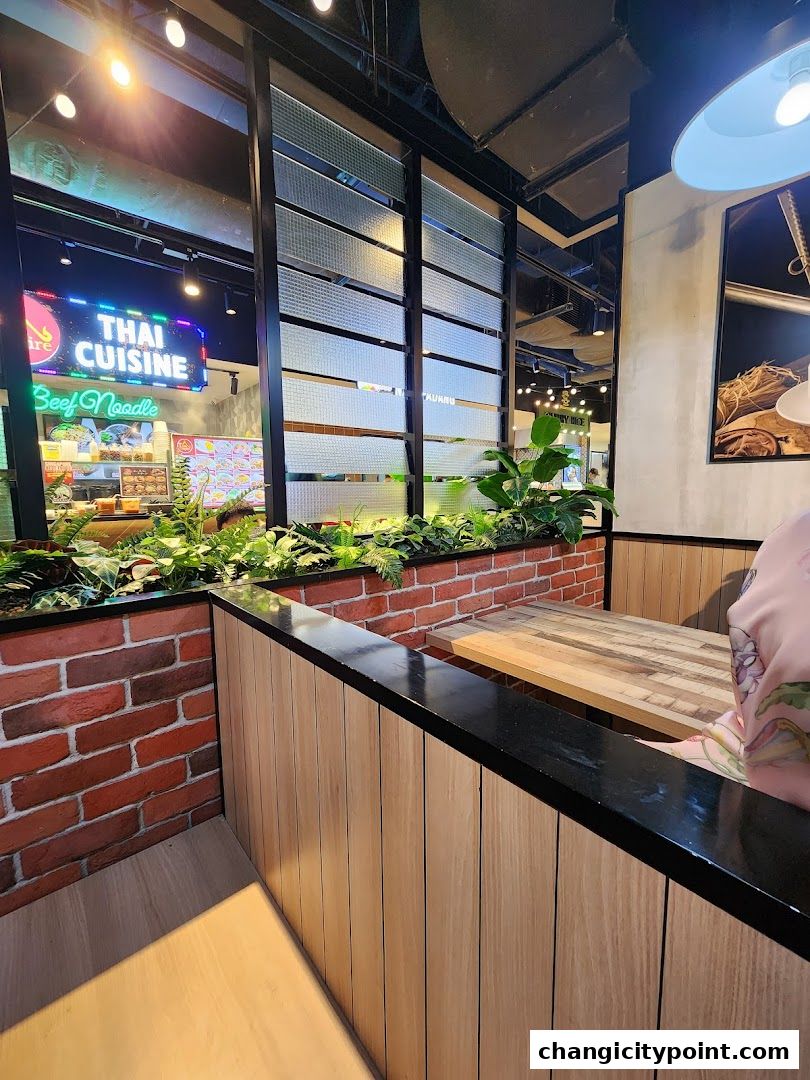 Interior view of a Thai cuisine restaurant with a neon sign and seating area.