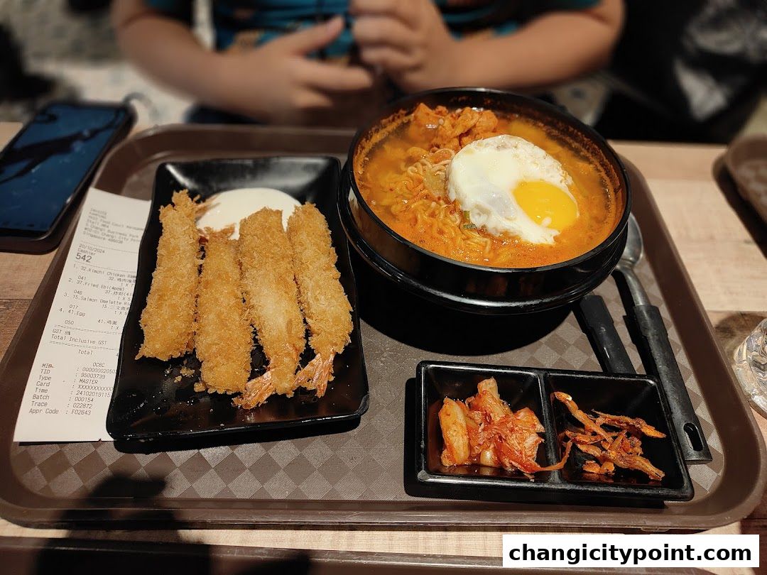 A tray of Korean food including fried shrimp, kimchi ramen, and side dishes.